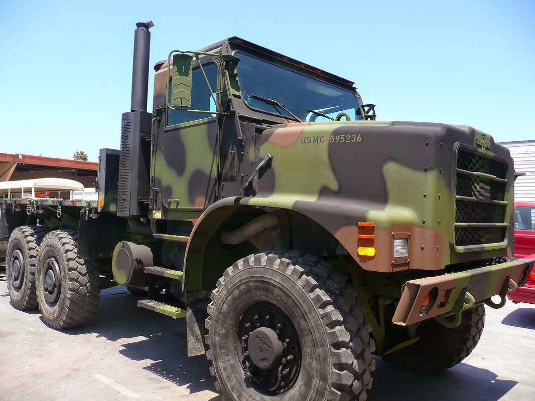 Camouflage-painted military 6x6 cargo truck with a tall exhaust stack